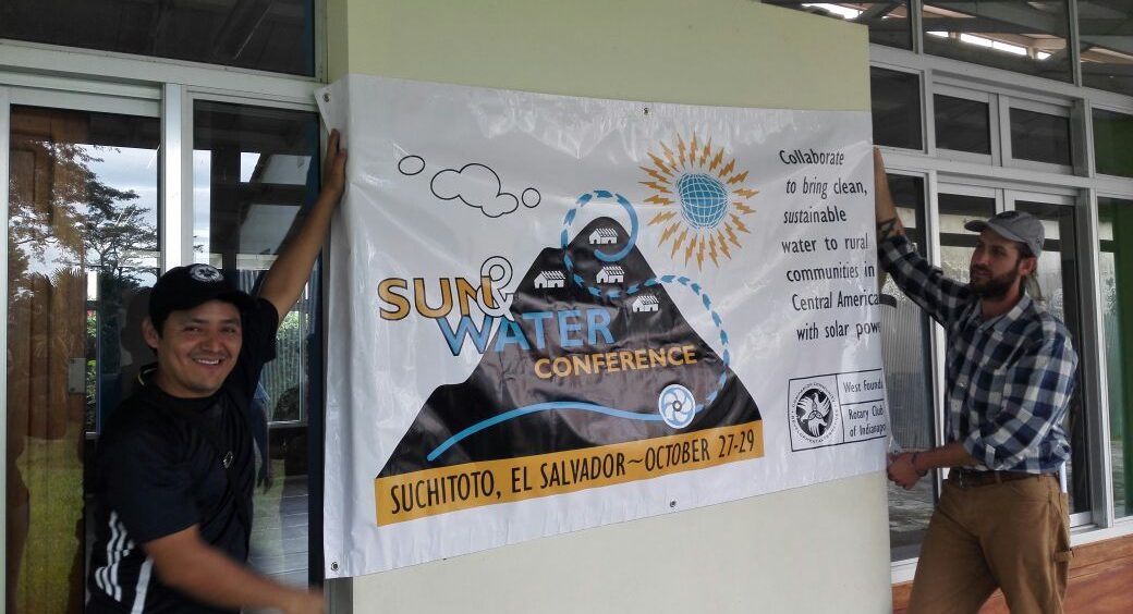 Two people display a banner that advertises a water conference.